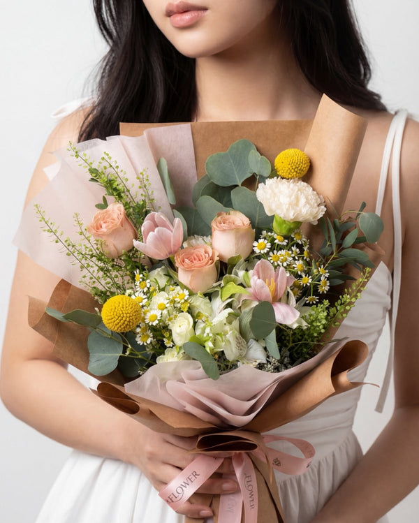 Better Days — peach roses, pink tulips and a white carnation with yellow billy balls, kraft paper wrap, held by a model