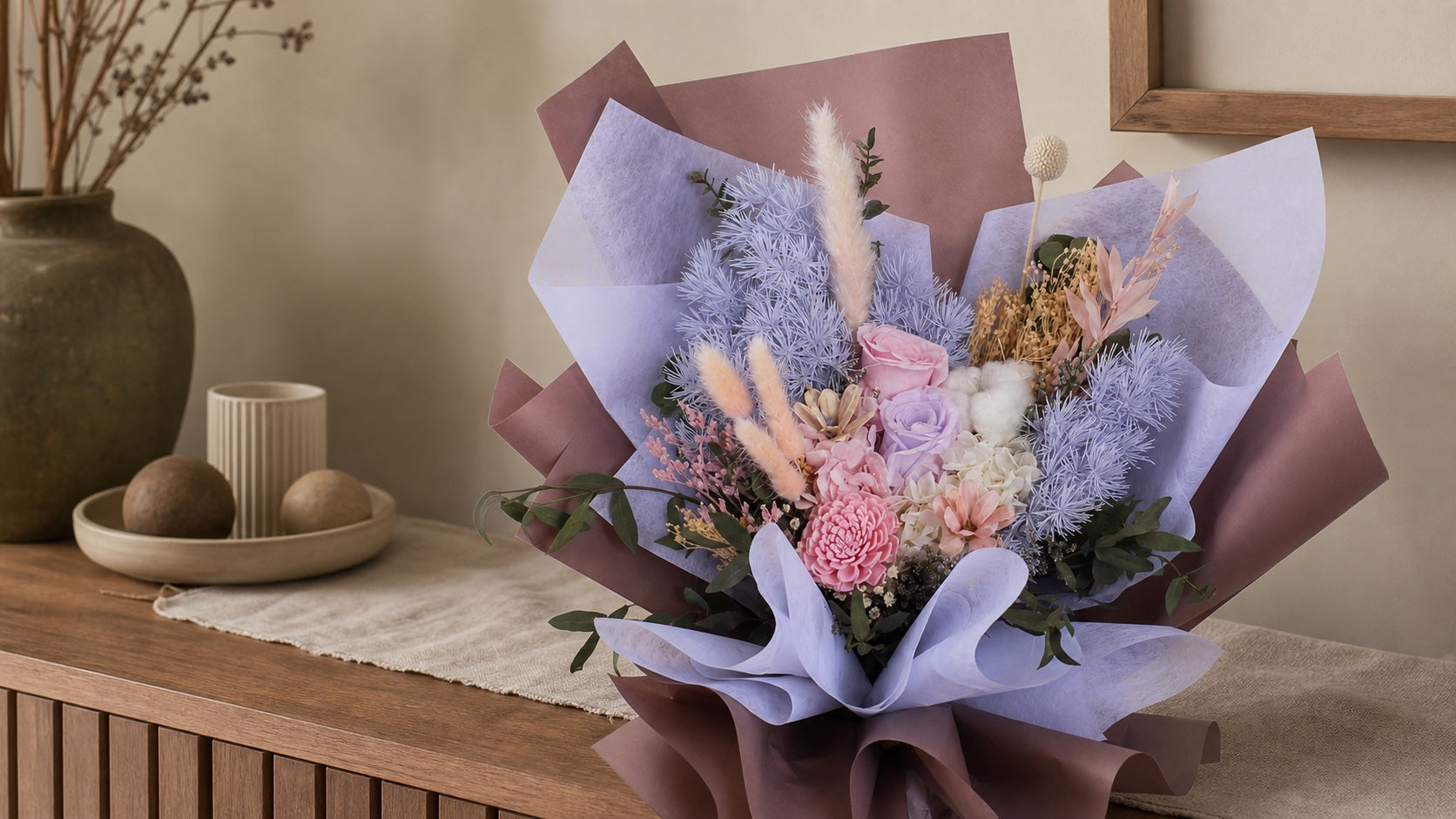 Preserved rose and dried flower bouquet on a shaded indoor console