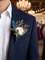 Corporate Boutonniere (White rose, blue bunny tail) worn on a navy blazer at a corporate gala