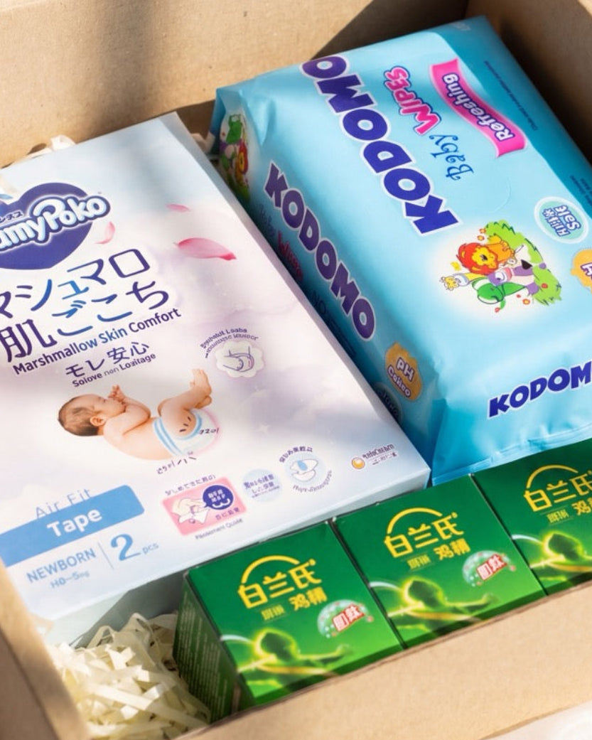 Close-up of baby essentials hamper Singapore showing MamyPoko Pampers, Kodomo wipes and BRAND'S Chicken Essence boxes