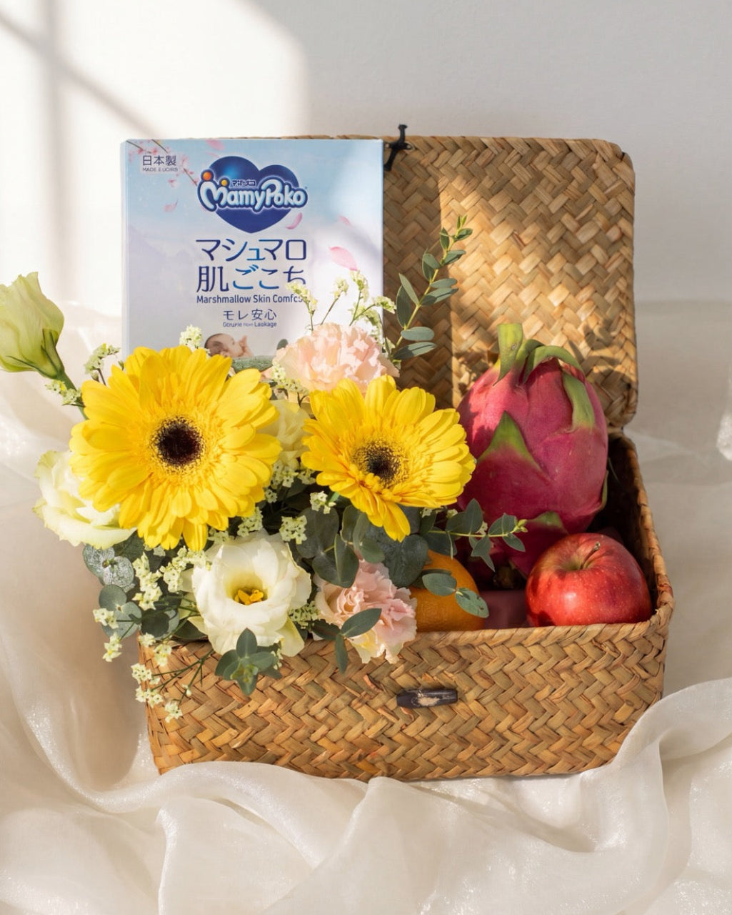 Baby hamper Singapore with MamyPoko Pampers, dragon fruit, apple, pear and yellow gerbera bouquet in a woven tray by Windflower Florist