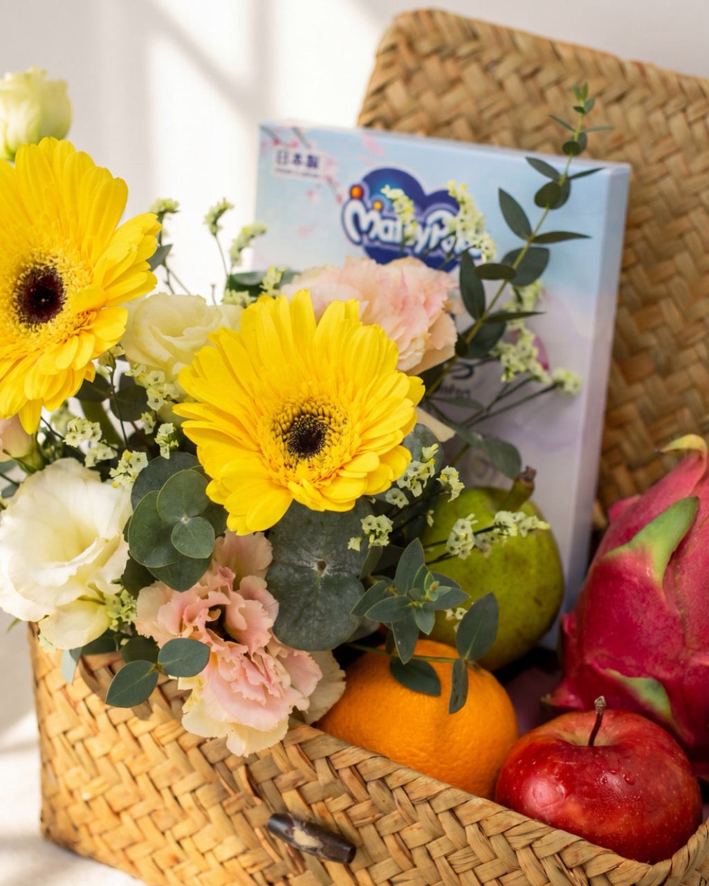 Close-up of baby hamper Singapore with flowers showing MamyPoko Pampers, fresh fruit and seasonal bouquet