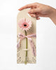 Single Stalk Gerbera Daisy Bundle — one pink gerbera daisy on a cream card sleeve tied with pink ribbon, held by hand