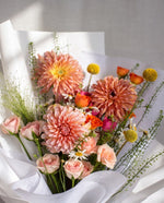 Akari — close-up of coral dahlias, peach roses and craspedia