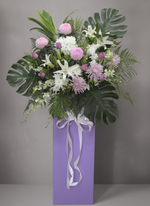 Blush Reverence condolence flower stand, white draping ribbon, trimmed foliage