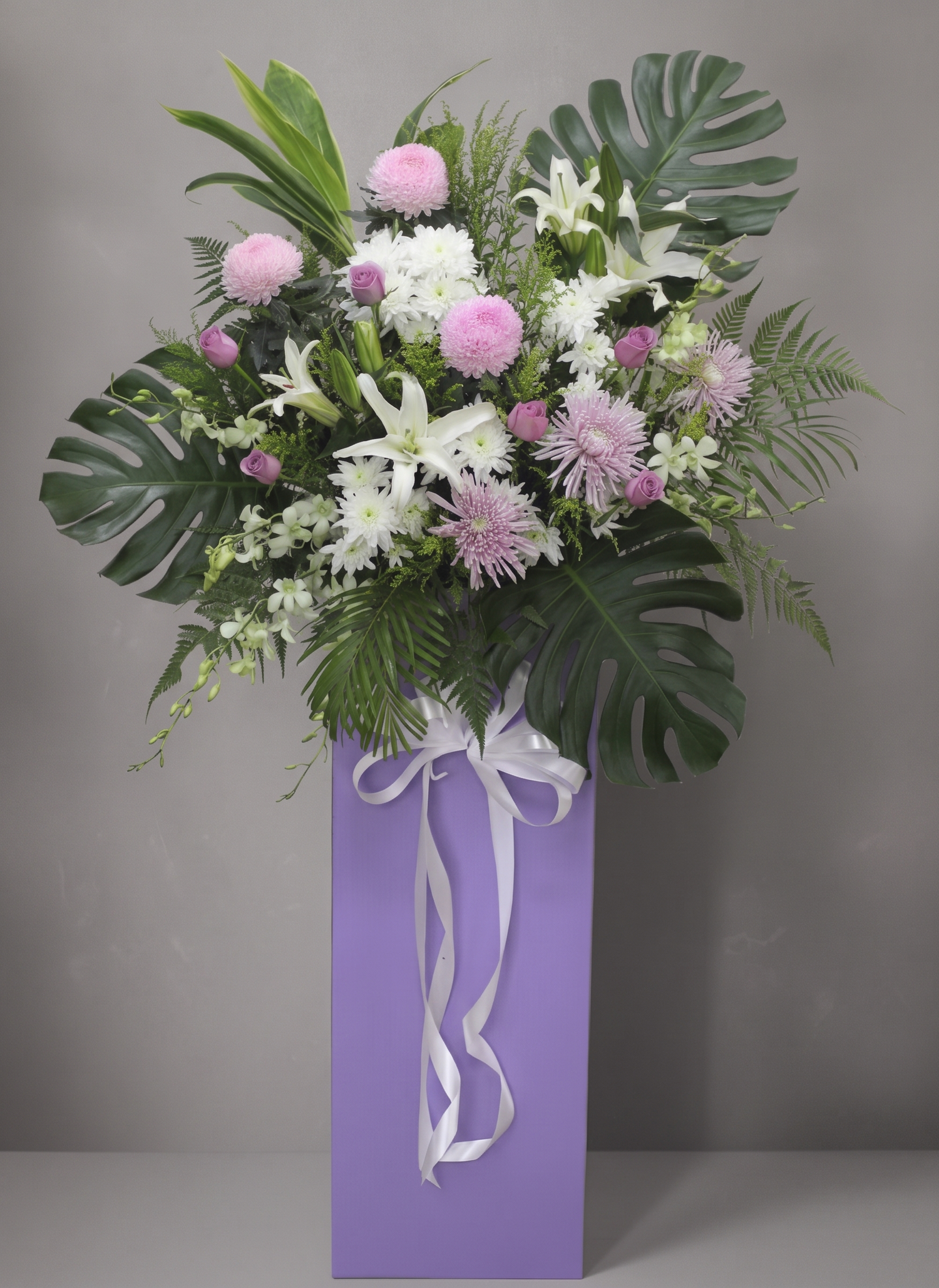 Blush Reverence condolence flower stand, white draping ribbon, trimmed foliage