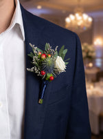 Corporate Boutonniere (White rose, blue thistle) worn on a navy blazer at a corporate gala