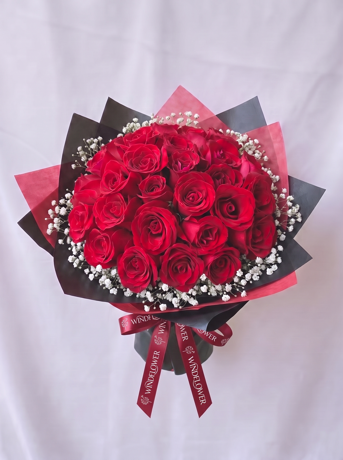 A Study in Red - Rounded, with baby's breath, white Windflower ribbon branding, natural drape and slant-cut tails